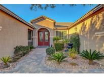 Charming front entrance showcasing a red door, beautiful landscaping and paved walkway at 6156 Twilight Cove Cir, Las Vegas, NV 89131