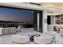 Modern living room with sleek bar and furniture, showcasing a city view through sliding glass doors at 667 Solitude Rock Ct, Henderson, NV 89012