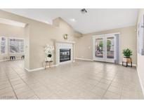 Bright living room featuring a fireplace, tile flooring, and French doors to outdoor space at 7624 Desert Delta Dr, Las Vegas, NV 89128