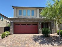 Beautiful two-story home with a brick driveway and a red garage door, located in a well-kept neighborhood at 11260 Burning River St, Las Vegas, NV 89183