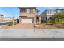 Two-story home with a two car garage, brick paver driveway and desert landscaping at 1338 Ossa St, Henderson, NV 89052