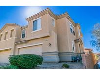 Two-story tan home with a two-car garage and manicured landscaping at 225 Priority Point St, Henderson, NV 89012