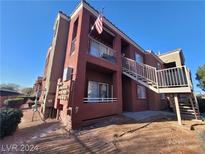 Two-story condominium building featuring a red exterior, balconies with white railings, and convenient stairwell access at 4730 E Craig Rd # 1106, Las Vegas, NV 89115