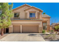 Two-story tan home featuring a two car garage and tile roof at 74 Harbor Coast St, Las Vegas, NV 89148