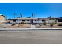 Charming single-story home featuring desert landscaping, a purple front door, and clear blue skies at 1631 Ottawa Dr, Las Vegas, NV 89169
