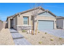 Charming single-story home with a desert-landscaped front yard and gray brick driveway under a clear blue sky at 2404 Elmont Ave, North Las Vegas, NV 89086