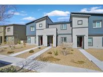 Modern townhome showcasing a gray facade, complemented by rock landscaping, a concrete walkway, and a blue sky backdrop at 527 Clearsable Ave, Henderson, NV 89044