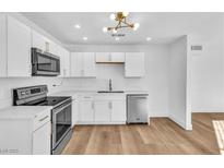 Bright kitchen featuring white cabinets, stainless steel appliances, and stylish light fixture at 6120 Kimberly Cir, Las Vegas, NV 89107