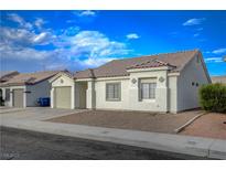 Charming single-story home featuring a well-maintained front yard with a one car garage and beautiful blue sky at , Las Vegas, NV 89106