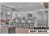 Bright kitchen features white cabinets, stainless steel appliances, and an island with counter seating at 10329 Bent Brook Pl, Las Vegas, NV 89134