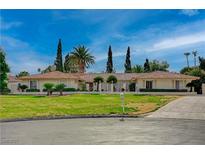 Expansive front yard view of a single story home with lush landscaping and a circular driveway at 208 Stonewood, Las Vegas, NV 89107