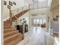 Bright entryway with wood staircase, modern railing, and open floor plan leads to the living room at 2737 Josephine Dr, Henderson, NV 89044