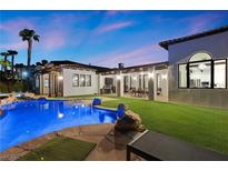 Inviting backyard pool area features a covered patio, lush green lawn, and beautifully designed landscaping at 3 Rue Allard Way, Henderson, NV 89011