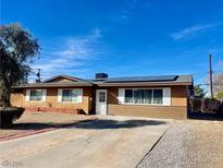 Single story home with xeriscape yard, brown wood facade, and solar panels on the roof at 3856 Commanche Ave, Las Vegas, NV 89121