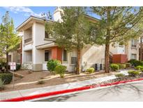 Condo exterior featuring neutral stucco, desert landscaping, trees, and private balcony at 913 Duckhorn Ct # 204, Las Vegas, NV 89144