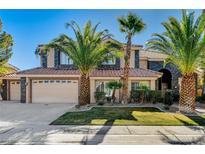 Inviting two-story home boasting a three-car garage, stone accents, tile roof, and lush landscaping with mature palm trees at 1859 Woodhaven Dr, Henderson, NV 89074