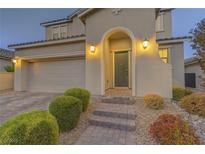 Inviting front entrance featuring an arched doorway, illuminated sconces and well-manicured landscaping at 426 Port Reggio St, Las Vegas, NV 89138