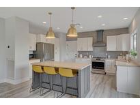 Modern kitchen with stainless steel appliances, gray backsplash and a large island with seating at 2602 Evening Sky Dr, Henderson, NV 89052