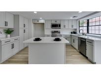 Bright kitchen features gray cabinets, stainless appliances, a kitchen island, and wood-look tile floors at 5151 Tennis Ct, Las Vegas, NV 89120
