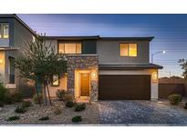 Two-story home featuring stone accents, a paved driveway, and a dark brown two-car garage at 10103 Eden Mountain St, Las Vegas, NV 89141