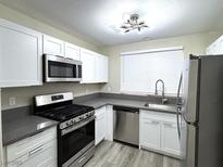 Well lit kitchen features stainless steel appliances, gray countertops, and white cabinets at 56 Belle Point Ave, Las Vegas, NV 89123