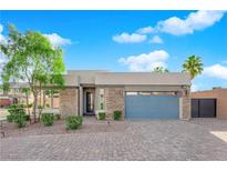 Charming single-story home featuring stone accents, manicured landscaping, and a blue garage door at 6325 Carmel Creek Ave, Las Vegas, NV 89139
