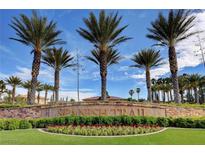 Spanish Trail community entrance featuring lush landscaping and mature palm trees under a bright blue sky at 7566 Spanish Bay Dr, Las Vegas, NV 89113