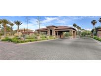Community entrance with paved road and landscaped median; welcome to the luxurious lifestyle that awaits in this exquisite community at 7566 Spanish Bay Dr, Las Vegas, NV 89113