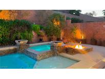 Inviting backyard pool with water features, fire pit, and lush landscaping, perfect for outdoor living at 3459 Ridge Meadow St, Las Vegas, NV 89135
