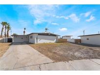 Charming home showcasing a desert landscape, complemented by palm trees against a bright blue sky at 1613 Hartke Pl, Las Vegas, NV 89104