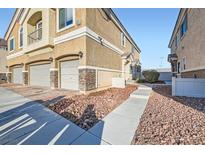 Charming townhome showcasing a well-maintained yard, attached two-car garage, and tasteful landscaping at 6637 Lookout Lodge Ln # 1, North Las Vegas, NV 89084