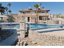 Backyard pool featuring a stone surround and view of a two-story home with second story balcony at 1828 Casa Vista Dr, Las Vegas, NV 89146