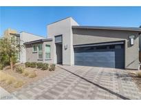 Modern home featuring a gray stucco facade, a two-car garage and a tiled driveway at 6842 Empire Cliff St, North Las Vegas, NV 89084