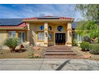 Inviting home featuring a terracotta roof, solar panels, and stone accents leading to the double-door entrance at 8880 W La Mancha Ave, Las Vegas, NV 89149