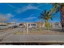 Modest single-story home featuring a chain-link fence, driveway, and various vehicles parked out front at 2716 Saint George St, North Las Vegas, NV 89030
