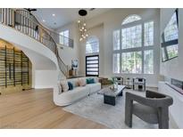 Bright living room features a curved staircase, modern furnishings, and an abundance of natural light at 5573 San Florentine Ave, Las Vegas, NV 89141
