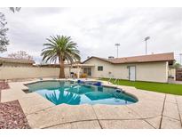 Backyard view of a sparkling pool with a palm tree, outdoor furniture and partially covered patio at 6309 Fairbanks Rd, Las Vegas, NV 89103