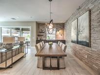 Open-concept dining room with a long wooden table, unique light fixtures, and a textured accent wall at 72 Reverie Heights Ave, Henderson, NV 89011