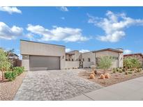 Contemporary home featuring a well manicured front yard and a gray brick driveway leading to an attached two car garage at 818 Calluna St, Las Vegas, NV 89138