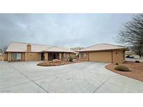 Spacious single-story home with a large driveway and separate two-car garage on a cloudy day at 1211 Bourbon St, Pahrump, NV 89048