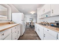 Bright kitchen features white cabinets, wood counters, stainless sink and views of dining area at 5272 Blanton Dr, Las Vegas, NV 89122