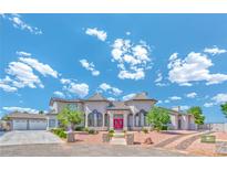Elegant two-story home featuring symmetrical design, a red door, and a manicured landscape at 6965 S Valley View Blvd, Las Vegas, NV 89118