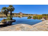 Gorgeous infinity pool overlooking a serene lake and mountain landscape with clear blue skies and palm trees at , Henderson, NV 89011