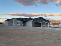A charming single-story home boasting a three-car garage, against a backdrop of distant mountains and a serene sky at 2530 S Tecumseh Ave, Pahrump, NV 89048