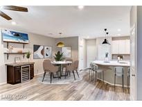 Bright dining area features a wine fridge, modern art and a round table for four at 2844 Alenga St, Henderson, NV 89044