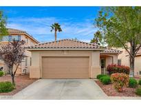 Charming single-story home with a two-car garage, tiled roof, and colorful landscaping at 11040 Napa Ridge Dr, Las Vegas, NV 89144
