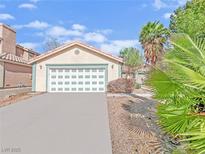 Two car garage featuring a white door on a well kept home with a large driveway at 498 Paulson Dr, Las Vegas, NV 89123