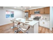 Modern kitchen features a quartz island with seating, stainless appliances, and wood-look cabinets at 5204 Doe Ave, Las Vegas, NV 89146