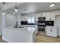 Modern kitchen with white cabinets, stainless steel appliances, an island and a black backsplash at 1225 Arrowhead Ave, Las Vegas, NV 89106