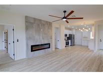 Open-concept living room featuring wood-look tile, modern fireplace, ceiling fan, and seamless flow into the kitchen at 3320 Herring Gull Ln, North Las Vegas, NV 89084